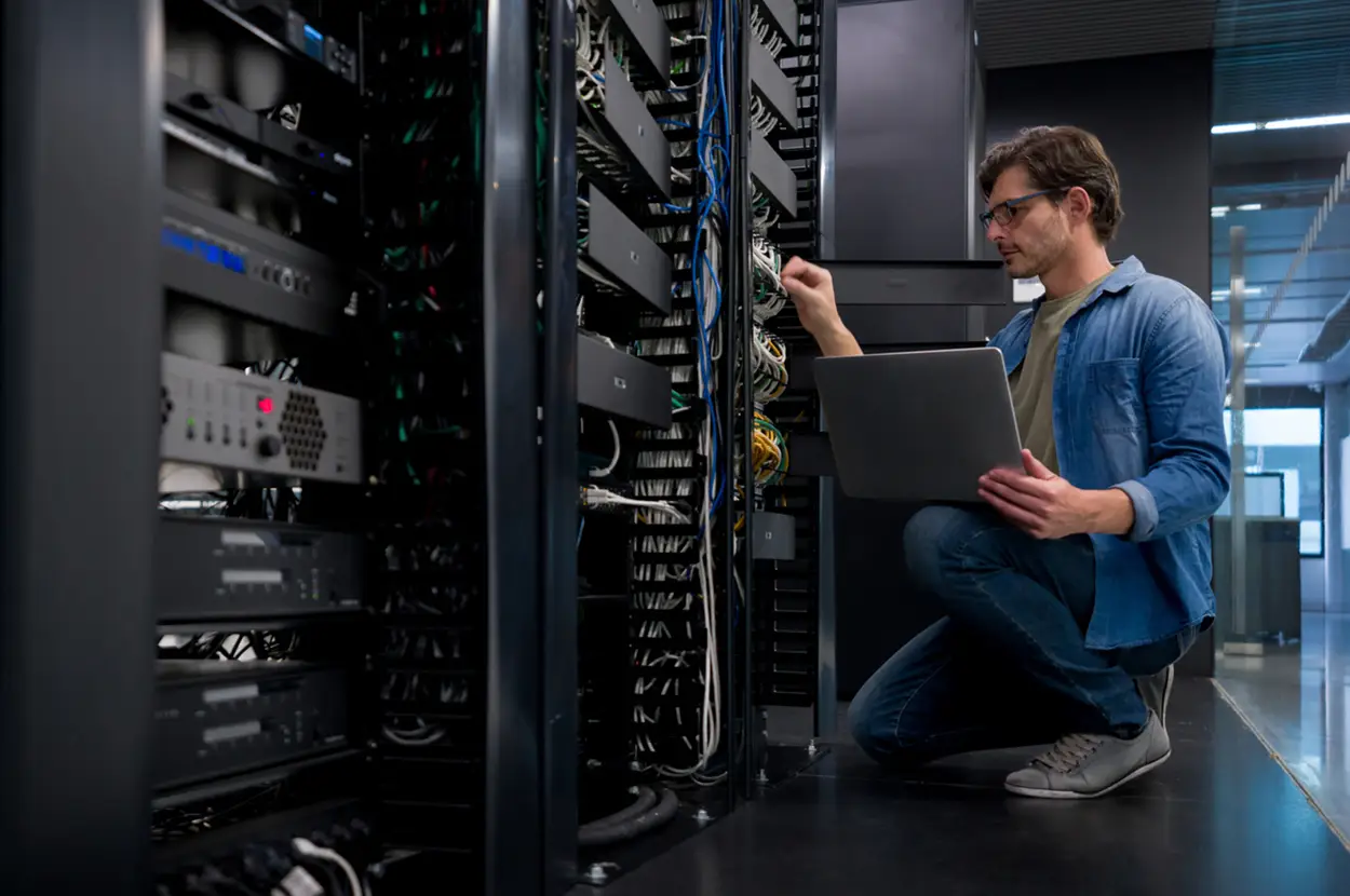 Technician working on a server rack with a laptop.
